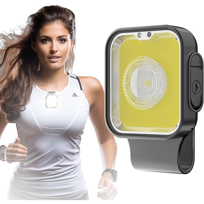 The light features a compact rectangular design with a bright yellow background and a central lens, designed to be clipped onto clothing for visibility during running. A model demonstrates its use while wearing a white athletic top, highlighting the product's practical application for outdoor activities.