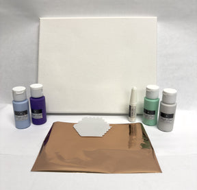 Art supplies including paint bottles, a canvas, and metallic paper on a white surface.
