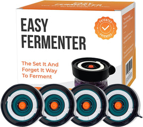 Four Easy Fermenter wide mouth lids are displayed in the foreground, each featuring a dark outer ring with a central orange dot and white detailing, while a box with an orange and white design is visible in the background, showcasing the brand name and product details.