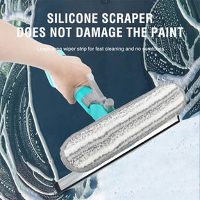 A hand holds the window cleaning squeegee featuring a silicone scraper and a microfiber cloth, demonstrating its use on a soapy glass surface. The image highlights the large-area wiper strip designed for effective and scratch-free cleaning.