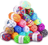 A colorful array of 23 acrylic yarn skeins in various shades, including bright oranges, pinks, blues, and greens, stacked in a pyramid shape. Each skein features a label with care instructions and brand name visible.