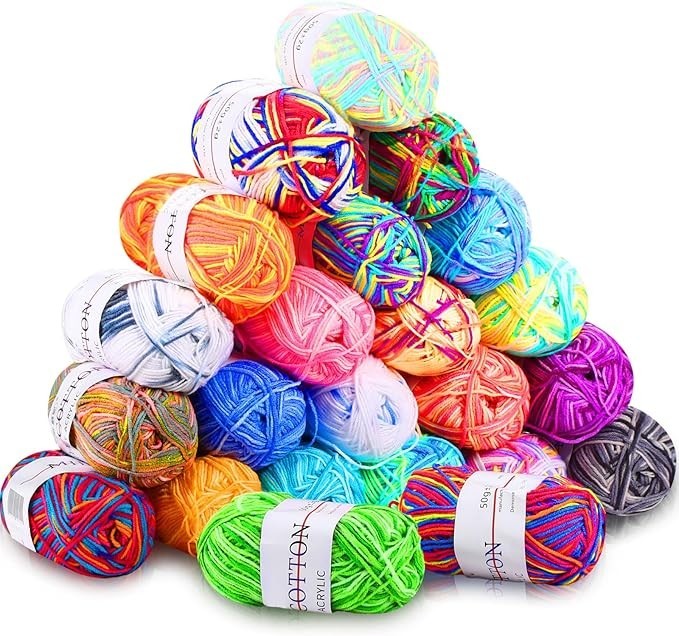 A colorful array of 23 acrylic yarn skeins in various shades, including bright oranges, pinks, blues, and greens, stacked in a pyramid shape. Each skein features a label with care instructions and brand name visible.