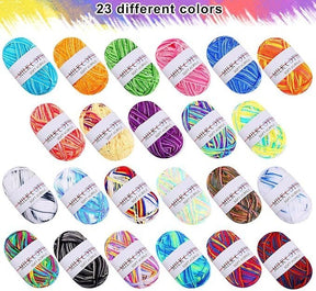 A vibrant assortment of 23 acrylic yarn skeins displayed in various colors, including shades of blue, green, orange, yellow, pink, purple, and more, all featuring a white label. Each skein is rounded and neatly arranged, showcasing the diverse palette available.