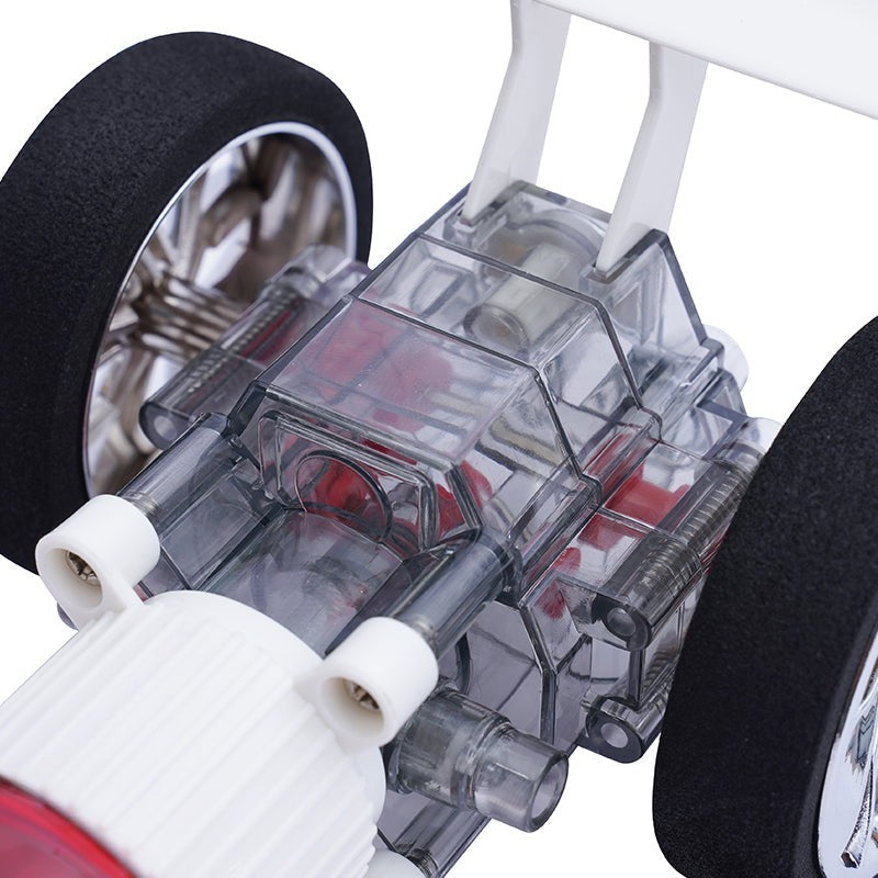 Close-up of the transparent chassis of the Atmospheric Inferno Turbo Racer, showcasing the intricate engineering with visible gears, tubes, and motor components, alongside a black rubber tire.