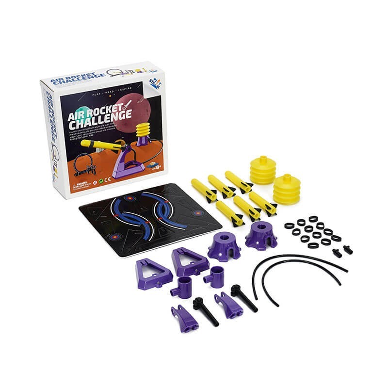 The image shows the PlaySTEAM Air Rocket Challenge kit, featuring a colorful box with a rocket launcher and various components including purple and yellow pieces, such as rocket fins, connectors, and a launch pad design. The arrangement showcases the different parts included in the set for assembling the rocket challenge.