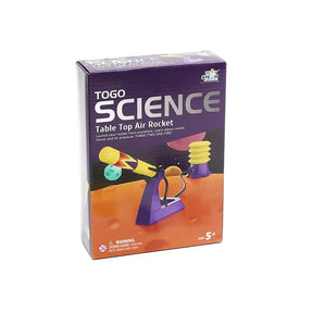 Colorful packaging for the PlaySTEAM Table Top Air Rocket features a rocket launcher with a yellow cone and a blue base, along with a rocket that has a fiery design. The box includes text highlighting the product's educational focus on rocket thrust and air pressure, suitable for ages 5 and up.