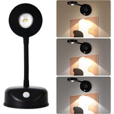 Black wireless motion sensor spotlight with a round head and flexible arm, designed to illuminate pictures or artwork. The spotlight features three different dimmable color options and is mounted on a base with a motion sensor.