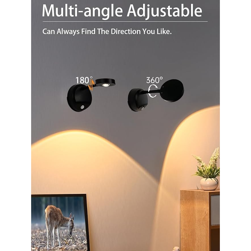 The image shows the Wireless Motion Sensor Picture Spotlight set at different angles, highlighting its adjustable features, with a sleek black finish against a soft-lit wall. A framed image of a deer is positioned below the spotlight, enhancing the lighting effect in the setting.