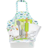 Colorful dinosaur-themed apron with a variety of baking tools including a rolling pin, spatula, whisk, cookie cutters, and baking sheet, all arranged neatly in a white container.
