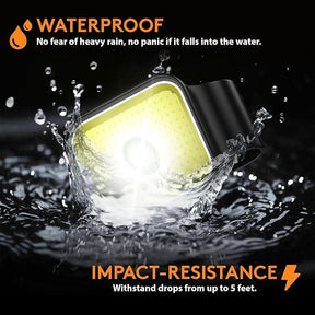 The running safety light is partially submerged in water, showcasing its waterproof feature, with a glowing yellow front and a black mounting clip on top, surrounded by splashes. The text highlights its waterproof and impact-resistant qualities.