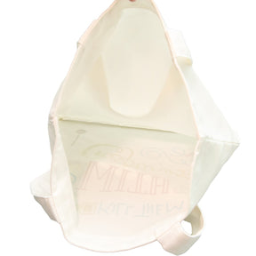 The canvas tote bag is shown from the side, featuring a cream color and colorful decorative text with various craft-related symbols. The bag has two sturdy handles for easy carrying.