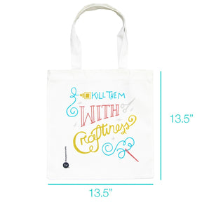 The white canvas tote bag features colorful, playful text that reads "Kill Them With Craftiness," adorned with decorative elements like a sewing needle, scissors, and swirls. It has two sturdy handles for easy carrying.