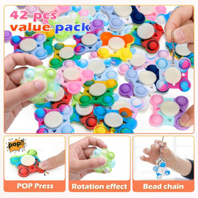 Colorful assortment of small fidget toys featuring various shapes, prominently a pop-press design, displayed together on a tray with hands demonstrating their use.