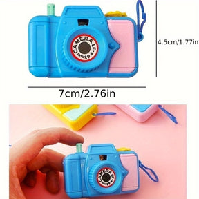 Bright blue toy camera with pink and yellow accents, measuring approximately 7cm by 4.5cm, held in a hand against a pink background.