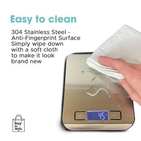 A hand is wiping the stainless steel surface of the digital food scale with a soft cloth, showcasing its anti-fingerprint feature. The display shows a weight reading of 45 grams.