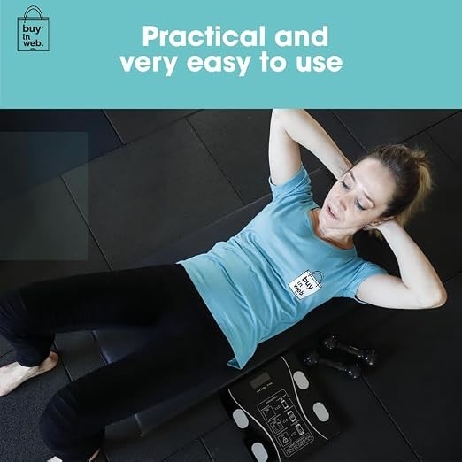 A woman wearing a light blue t-shirt is doing crunches on a black mat, with a smart scale and dumbbells visible beside her. The background features a clean workout space, emphasizing a practical fitness lifestyle.