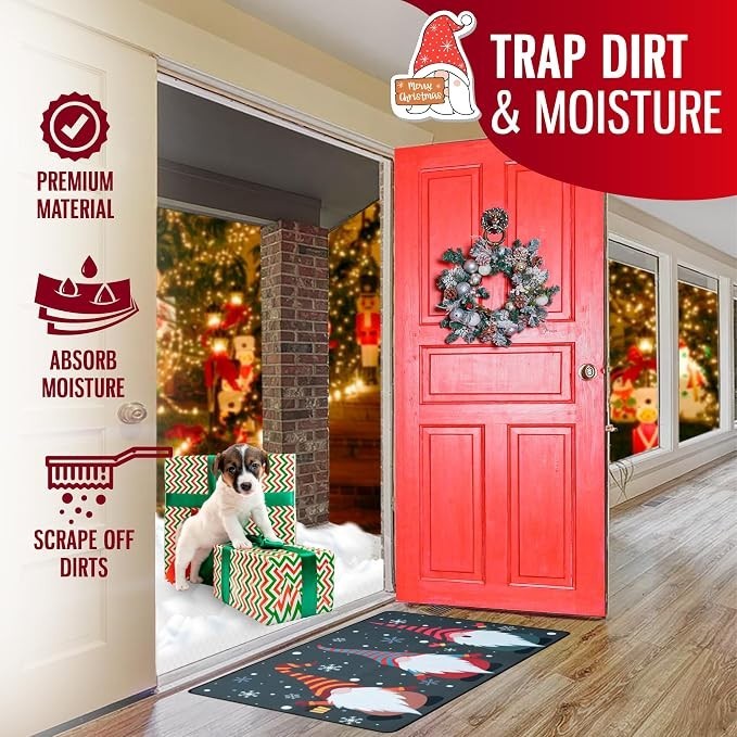 The doormat features a festive design with gnomes against a dark background, positioned near a red door decorated with a wreath. A small dog sits on a gift box beside the doormat, which lies on a wooden floor inside a brightly lit room adorned with Christmas decorations.