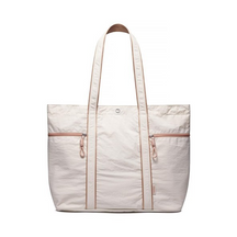 Large off-white canvas tote bag featuring two zippered pockets and tan accents, with thick shoulder straps for easy carrying.