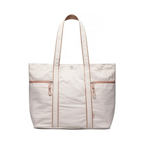 Large off-white canvas tote bag featuring two zippered pockets and tan accents, with thick shoulder straps for easy carrying.
