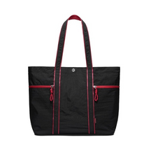 Spacious black canvas tote bag featuring bright red zippers and stitching, dual shoulder straps, and a sturdy design suitable for heavy-duty use. Two front zippered pockets add functionality and style.