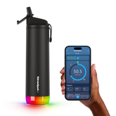 The sleek black 21 OZ HidrateSpark Pro Smart Water Bottle features a colorful, illuminated base and a convenient flip-top lid. Next to the bottle, a hand holds a smartphone displaying the HidrateSpark app interface with hydration tracking details.