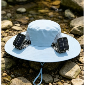 A light blue unisex solar fan hat features two solar panels on the sides, showcasing a wide brim and mesh detailing for ventilation, set against a rocky outdoor background.