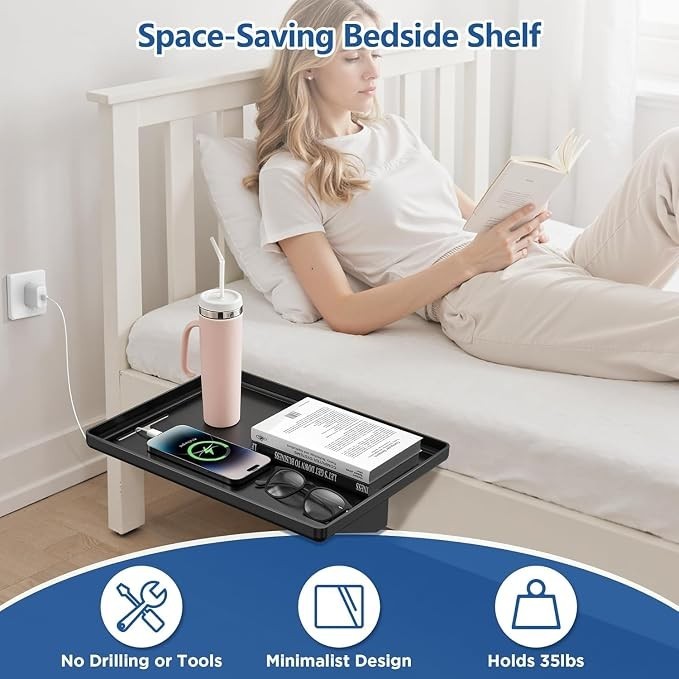 A woman is comfortably seated on a bed, reading a book while using the clamp-on bedside shelf, which holds a smartphone, a pair of glasses, and a pink water tumbler. The shelf is positioned against the bed, demonstrating its space-saving, minimalist design.