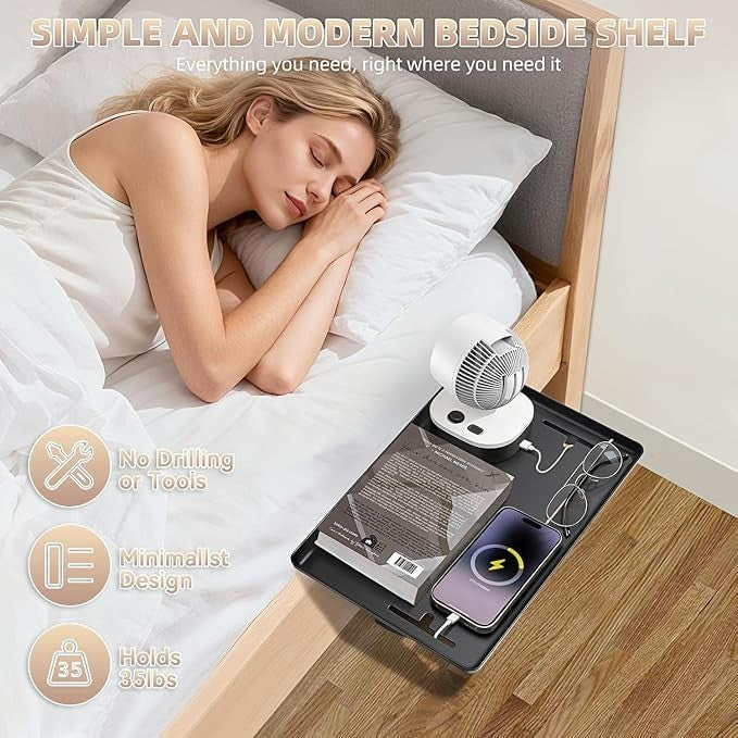 A woman is sleeping in bed next to a black clamp-on bedside shelf holding a phone with a charging icon, a pair of glasses, a book, and a small fan. The shelf displays a modern minimalist design, seamlessly integrated into the bed's side.