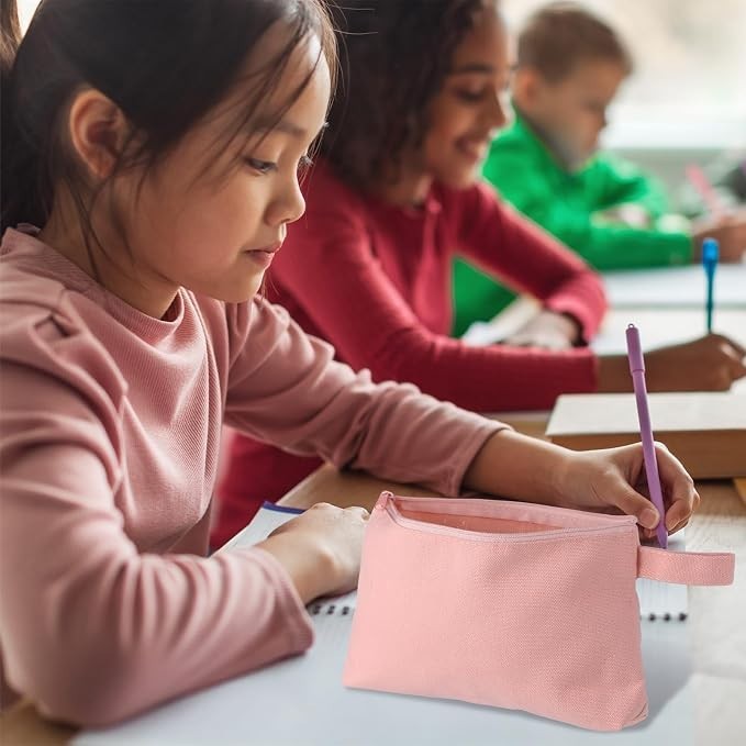 A pink canvas zippered pouch sits on a desk in front of a child, who is writing in a notebook. Two other children can be seen in the background, engaged in similar activities.