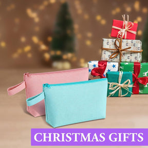 Two zippered canvas pouches in pink and light blue are displayed in front of a blurred background with festive Christmas gifts stacked together. The pouches feature a zip closure and small wrist straps.