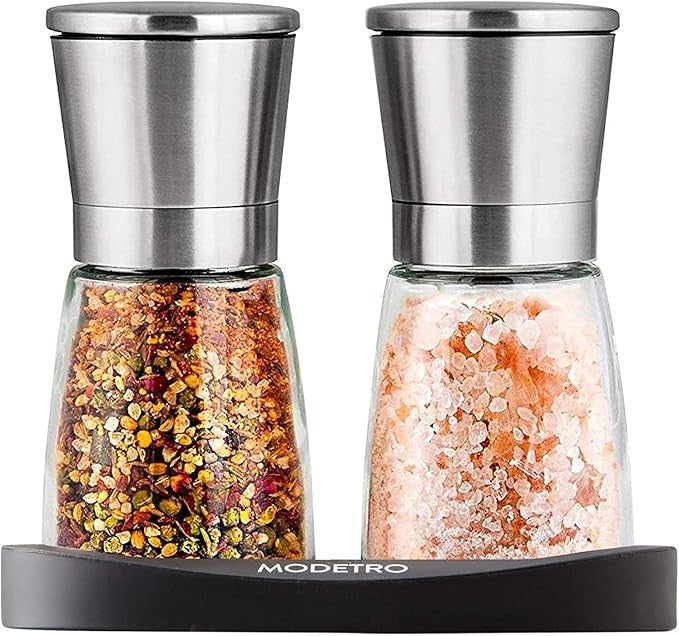 Stylish salt and pepper shakers set featuring a sleek stainless steel top and clear glass bodies, one filled with coarse pink salt and the other with a colorful spice blend, resting on a black stand.