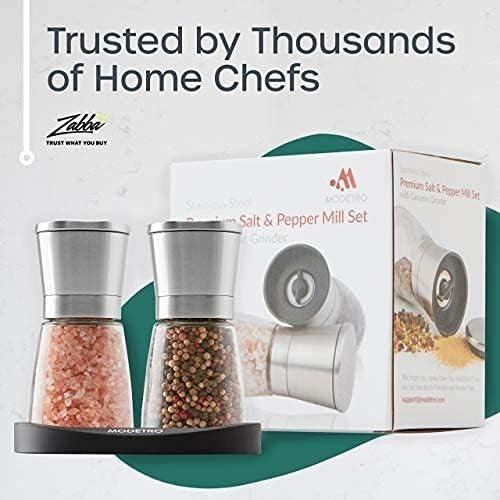 Stylish salt and pepper shakers with stainless steel tops and glass containers filled with pink Himalayan salt and mixed peppercorns, displayed on a sleek black base alongside packaging that features the Modetro logo.