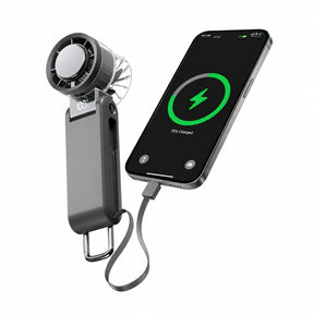 Compact black handheld fan with a digital display showing battery percentage, connected to a smartphone via a charging cable, illustrating its dual function as a fan and power bank.