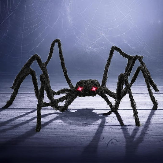 Large black furry spider with long legs and glowing red LED eyes is positioned on a wooden surface, creating a spooky ambiance perfect for Halloween decor.