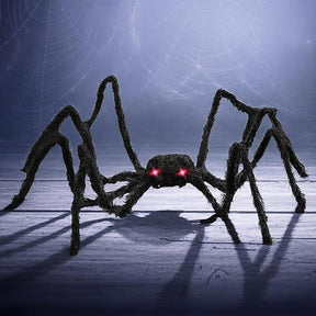 Large black furry spider with long legs and glowing red LED eyes is positioned on a wooden surface, creating a spooky ambiance perfect for Halloween decor.