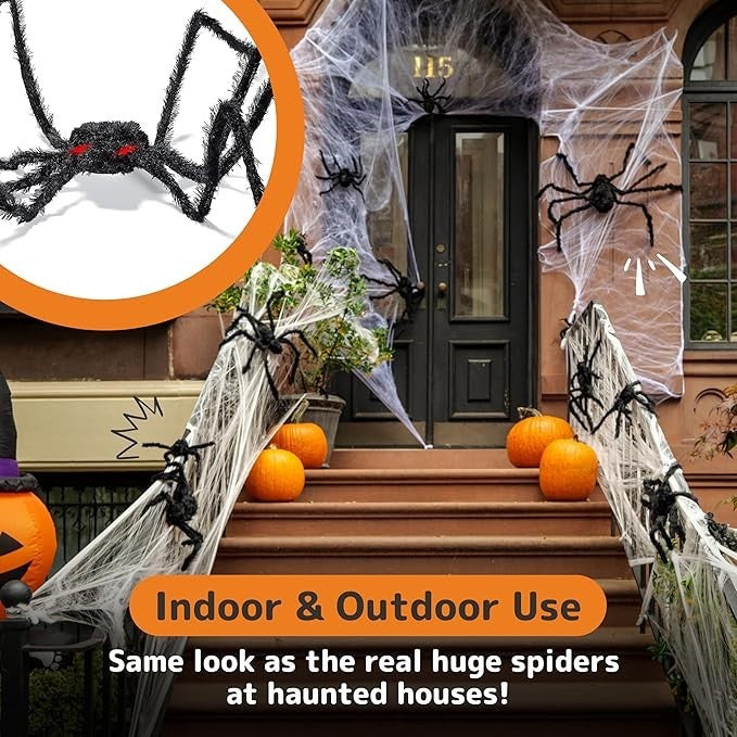 A large, hairy black spider with glowing red eyes is positioned among orange pumpkins and decorative cobwebs on a staircase leading to a front door, showcasing its suitability for Halloween decoration. The setting is a home entrance, enhancing the spooky theme.