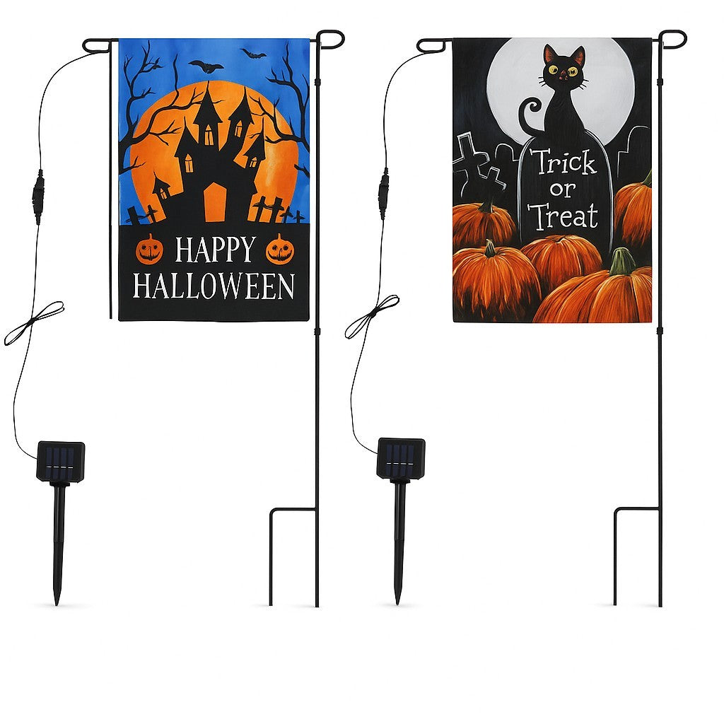 Two Halloween-themed solar garden flags are displayed; the left features a haunted house under a full moon with "Happy Halloween" text, while the right shows a black cat beside a "Trick or Treat" tombstone and pumpkins. Each flag is mounted on a black metal stand with a solar panel at the base for illumination.
