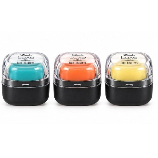 Three round lip balm containers with clear lids showcasing teal, orange, and yellow balms, each sitting in sleek black bases.