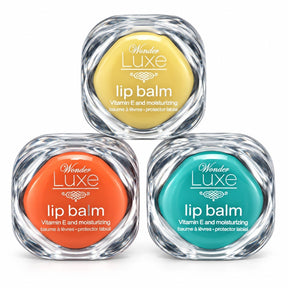 Three assorted flavors of Wonder Luxe Lip Balm in yellow, orange, and teal containers are displayed. Each container features a clear plastic design and text indicating they are moisturizing lip balms enriched with Vitamin E.