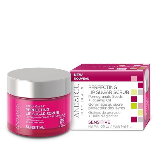The product features a round, clear jar filled with a bright pink lip sugar scrub labeled "1000 Roses Perfecting Lip Sugar Scrub," accompanied by a coordinating box showcasing similar colors and text in both English and French. The jar is topped with a silver lid and the box emphasizes its sensitive formulation with a "NEW" label.