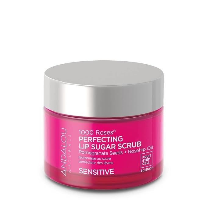 The jar contains a vibrant pink lip sugar scrub with a sleek silver lid, labeled "1000 Roses Perfecting Lip Sugar Scrub" featuring pomegranate seeds and rosehip oil, designed for sensitive skin. The overall design highlights a modern and floral aesthetic.