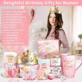 A woman wearing a crown holds a gift box with "HAPPY BIRTHDAY!" while surrounded by various pink-themed birthday gifts, including a ceramic mug, bath bomb, and a greeting card, all set against a soft background with balloons.