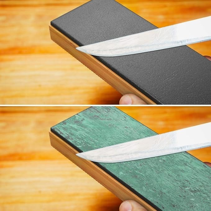 The image displays a double-sided leather strop sharpener, showing a black side on the top half and a green side on the bottom half, each with a knife being sharpened against them. The strop has a wooden base that highlights its sturdy design.