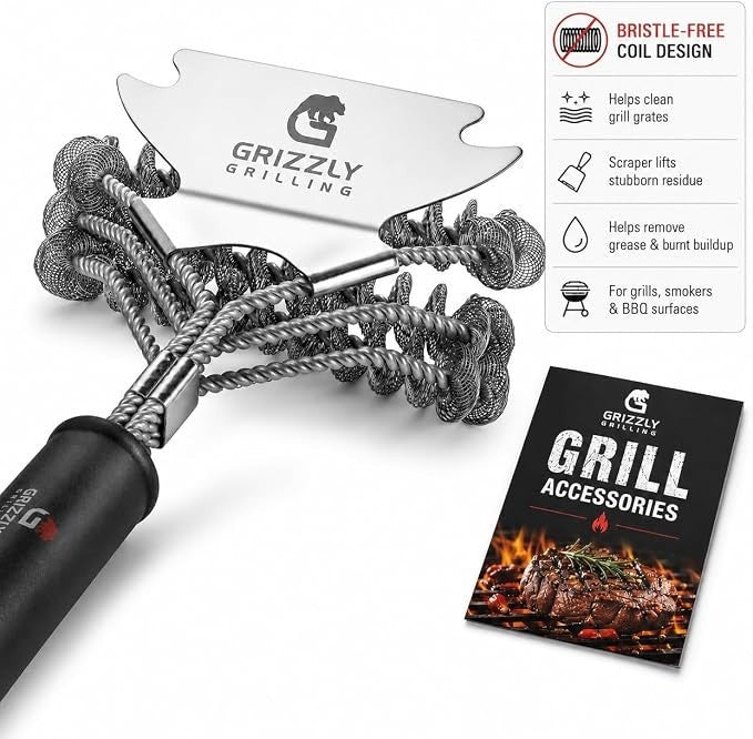 Close-up view of the Grizzly Grilling Bristle Free Grill Brush featuring a stainless steel scraper and coil design, with a black handle for a secure grip, alongside a promotional booklet for grill accessories.