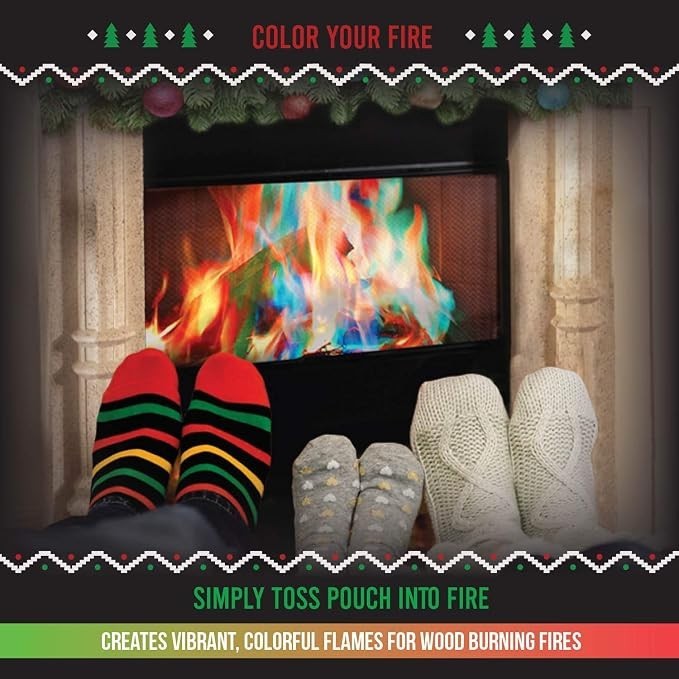 Colorful flames in a fireplace with red, green, blue, and orange hues, while two pairs of feet in festive socks and cozy slippers rest in front of the fire. Decorative elements above include festive greenery.