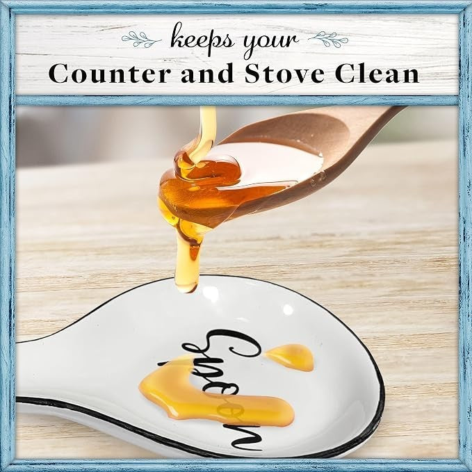 Ceramic spoon rest with a black rim features the word "Spoon" in a decorative font, catching drips of honey from a wooden spoon, set on a wooden countertop.