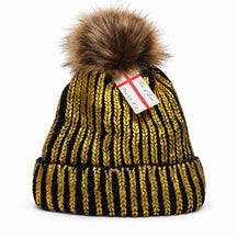 This winter beanie is designed with alternating gold and black stripe patterns, featuring a fluffy brown pom-pom on top and a warm fleece lining for added comfort. The bottom edge has a thick knitted cuff for a snug fit.