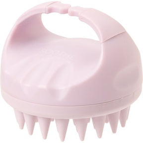 The scalp massager features a rounded, pink design with a comfortable handle and soft silicone bristles on the underside for gentle stimulation. Its compact size and ergonomic shape make it easy to hold and use.